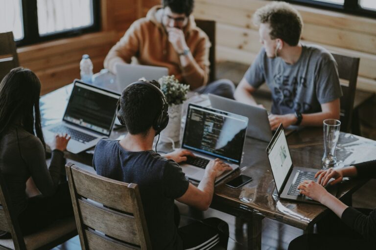 Team di software engineering che discute codice e architettura, sfondo schermi con linee di codice